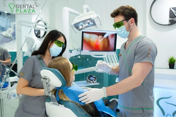 Zubar i zubarka sa pacijentom u ordinaciji na saniranju zubnog kamenca.